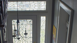 A staircase leading to a room with a stained glass door, a chandelier, and a doormat. - Artistic Lodging Queen suite (Paris)