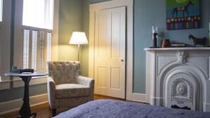 A room with a chair, a table, a lamp, a door, and a fireplace. - Artistic Lodging Queen suite (Paris)