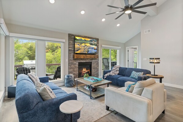 A spacious living room with a fireplace, two sofas, a coffee table, and a ceiling fan.