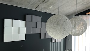 A modern dining area with a dark wall, geometric white and gray wall art, and two spherical hanging lights. - Design Villa Winterberg: Luxury vacation home directly on the slopes/meadow (Winterberg)