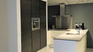 A modern kitchen with a central island, built-in oven, and stainless steel appliances. - Design Villa Winterberg: Luxury vacation home directly on the slopes/meadow (Winterberg)