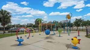 Un patio de juegos al aire libre con diversas estructuras, incluyendo columpios, un rocódromo y una piscina de pelotas.