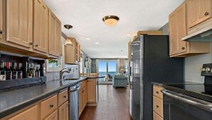 A modern kitchen with wooden cabinets, stainless steel appliances, and a view to the outside. - WATERFRONT DOOR COUNTY HOME.  Gorgeous Sunsets. 3 Bedrooms. Sleeps 6.   5 star! (Door County)