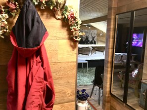 A room with a wooden floor, a bed with a white bedspread, a small table, and a chair. There is a coat hanging on the wall and a vase with flowers on a table. - Chalet-style vacation apartment on the shores of Lake Chiemsee ✔ Newly renovated ✔ 3 minutes from the lake (Feldwies)