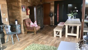 Una sala de estar acogedora con piso de madera, un sillón estampado, una mesita y un aparador.