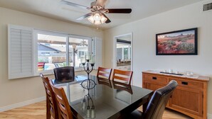 A dining area with a glass table, wooden chairs, a ceiling fan, and a view of the outside. - PET FRIENDLY IN QUIET NEIGHBORHOOD! (Tempe)