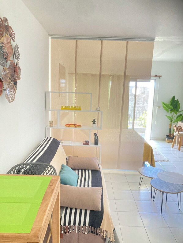 Un salon moderne avec un canapé, une table basse et une porte-fenêtre coulissante donnant sur un balcon.