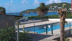 A pool area with a view of the sea and a hill in the background. - Studio Bougainvillier Style Bohème (Marigot)