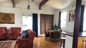 Een ruime woonkamer met een rode bank, een houten eettafel en een keuken met een bar.