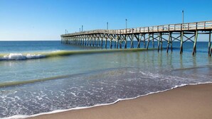 Eine Pier, die sich in ruhiges Wasser erstreckt, mit wolkenlosem Himmel.