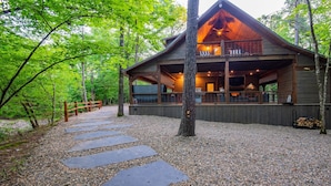 A cabin with a covered deck and a stone pathway leading to it.