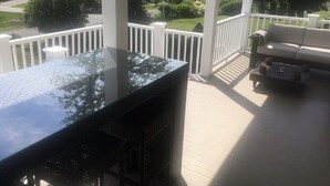 A covered patio with a black table and white railings.