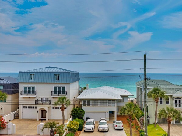 A coastal residential area with houses, a clear sky, and the ocean in the background.