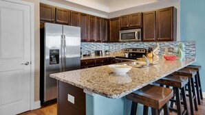 Una cocina moderna con armarios de madera oscura, electrodomésticos de acero inoxidable, encimera de granito y una pared de acento azul.