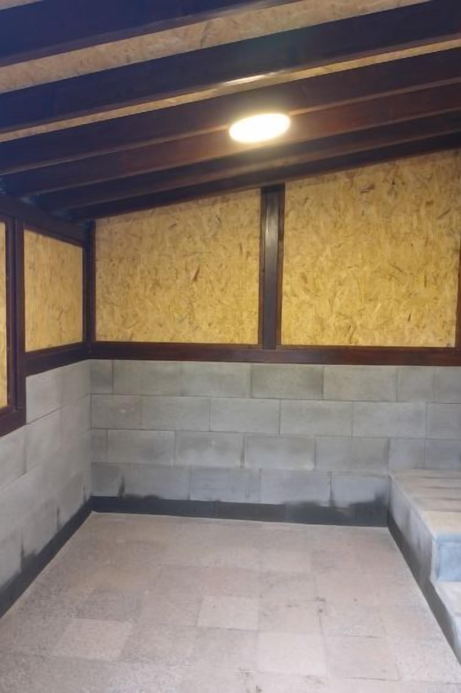 A room with exposed wooden beams, a concrete block wall, and a tiled floor.