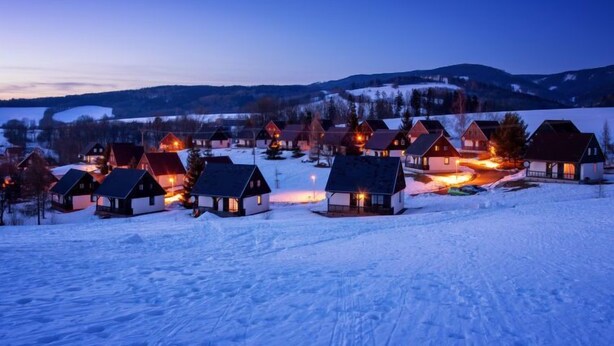 A snow-covered village with houses and a mountain backdrop during twilight. - Holiday Hill 26 by Interhome (Cerny Dul/Cista)