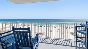 A balcony with a view of a beach, a railing, and a few chairs. - STUNNING 4TH FLOOR GULF FRONT CORNER UNIT with bunk beds (Pensacola)