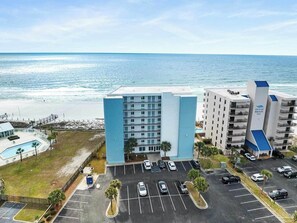 Ein Hotel mit Pool, Parkplatz und Meerblick.