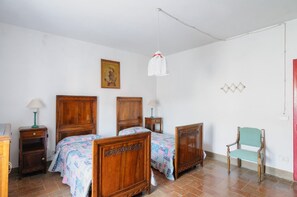 Two beds with matching headboards and footboards, each with a colorful quilt, and a bedside table with a lamp on either side.