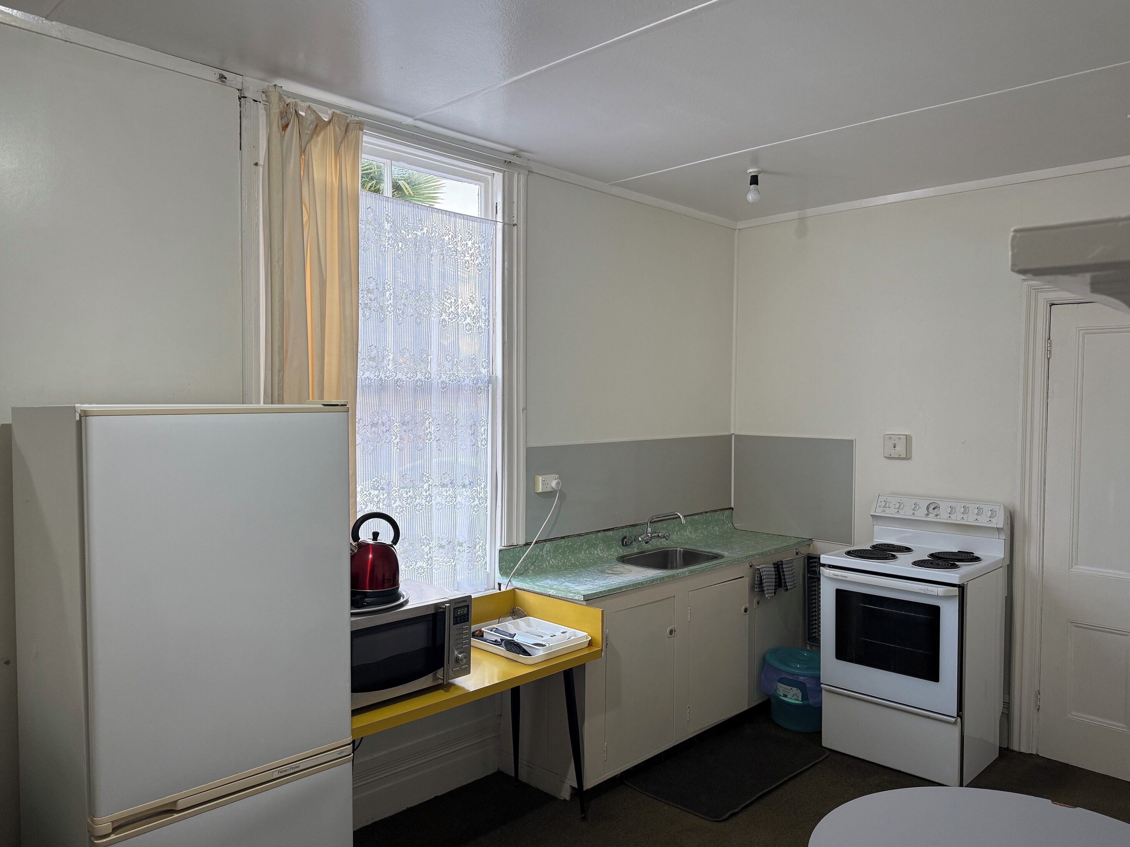 Una cocina compacta con refrigerador, microondas, estufa y una pequeña encimera.