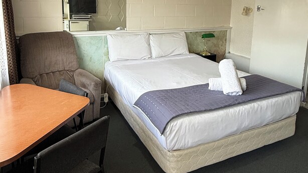A hotel room with a bed, a desk, a chair, a television, and a mirror. - Taihape Motel (Taihape)