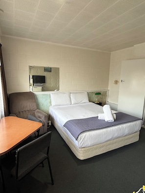 A hotel room with a bed, a desk, a chair, a television, and a mirror. - Taihape Motel (Taihape)