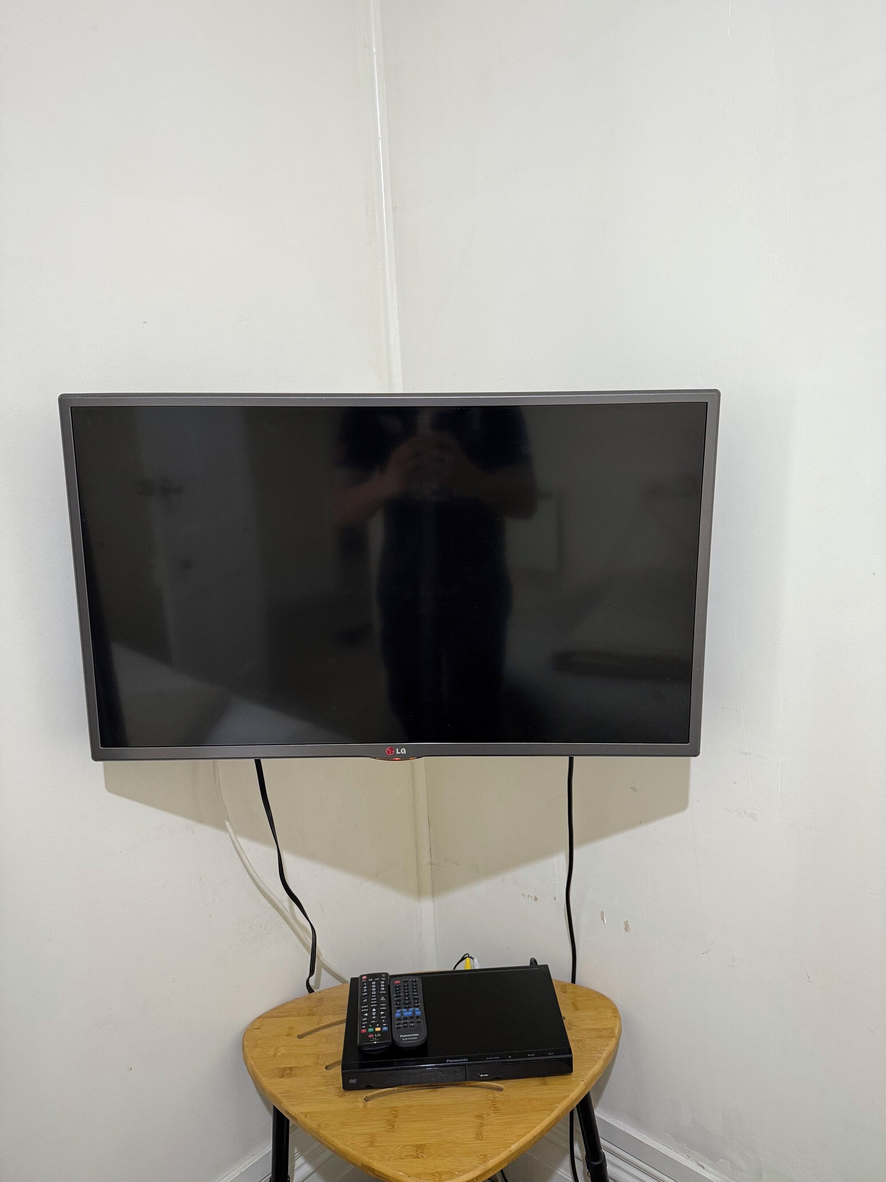 Un televisor de pantalla plana montado en la pared, con una mesa de madera debajo.