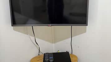 Un televisor de pantalla plana montado en la pared, con una mesa de madera debajo.