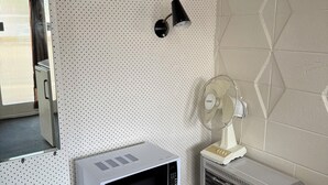 A kitchenette with a microwave, a fan, and a wall-mounted lamp. - Taihape Motel (Taihape)