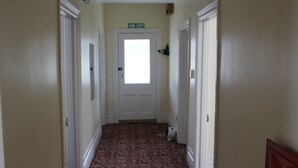 A hallway with a fire exit sign, carpeted floor, and white doors. - Taihape Motel (Taihape)