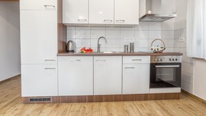A modern kitchen with white cabinets, a stainless steel stove, and a wooden countertop. - Luxury Apartments Iva (Vodice)
