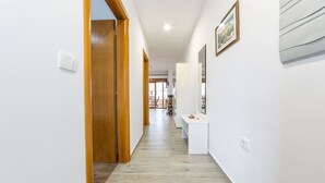 A hallway with wooden doors, white walls, and a tiled floor. - Luxury Apartments Iva (Vodice)