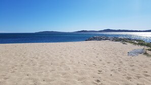 Enjoy a serene beach experience with a clear view of the surrounding hills and calm sea.