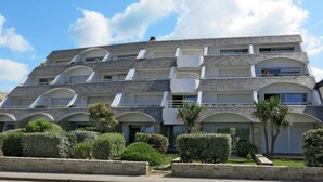 Un hotel de varios pisos con fachada simétrica, varios balcones y un jardín delantero ajardinado.
