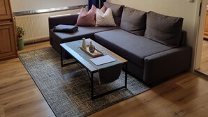 Uma sala de estar moderna com um sofá cinzento, uma mesa de centro de madeira e um tapete estampado.