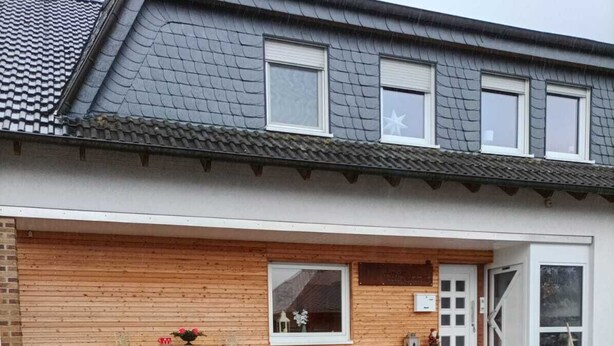 A two-story house with a tiled roof, a wooden facade, and a brick foundation. - Large family-friendly apartment for 2 - 5 people on the first floor. (Rheinland-Pfalz - Beuren (Eifel))