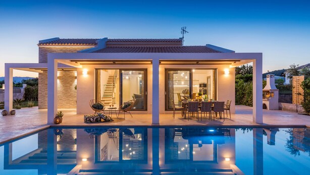 A modern house with a swimming pool, large glass doors, and a well-lit patio area. - Villa Anemona - Zante Prime Heated Pool Villas  (Zakynthos)