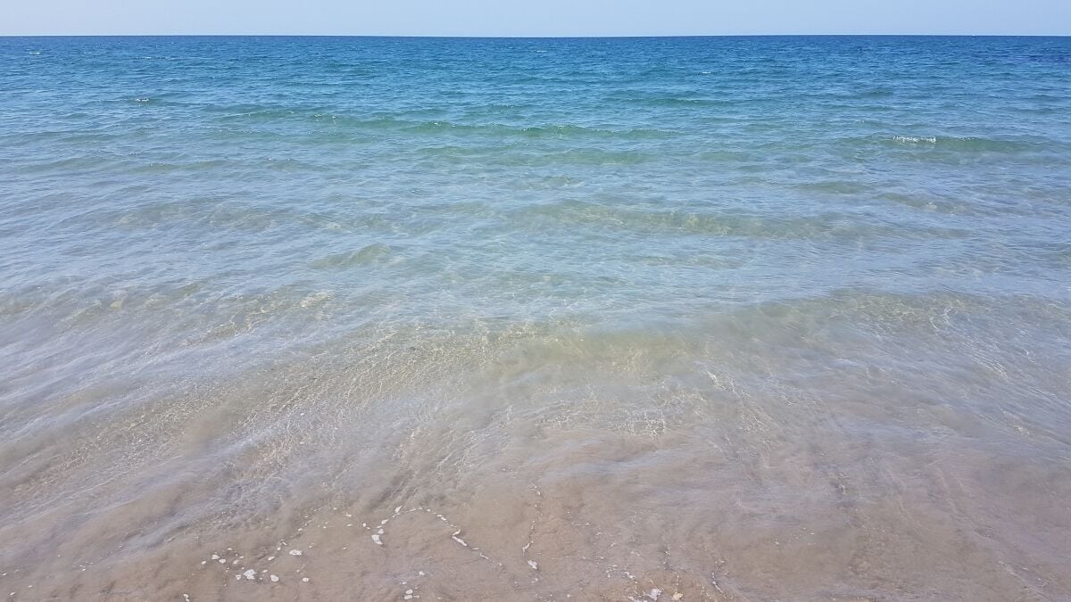 A beach with clear water and sandy shore.