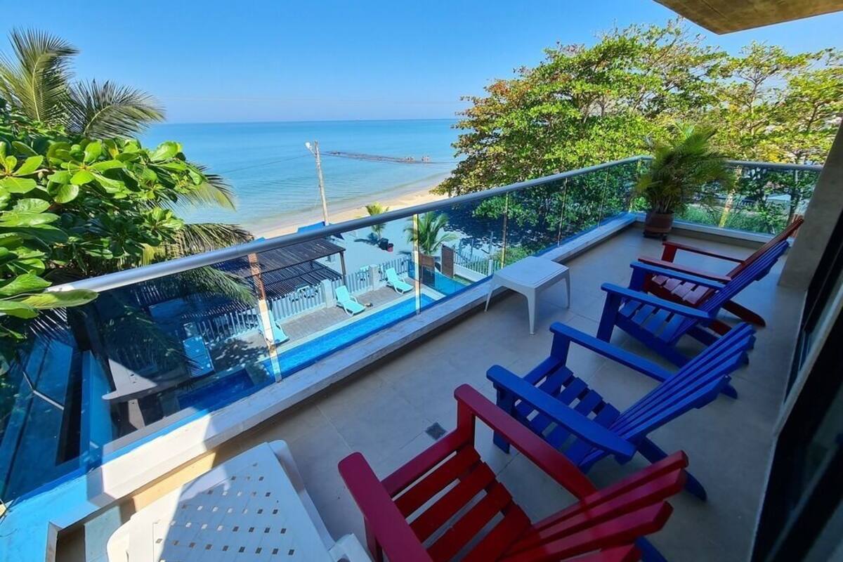 Un balcon offrant une vue dégagée sur la plage, une piscine et des chaises aux couleurs vives.