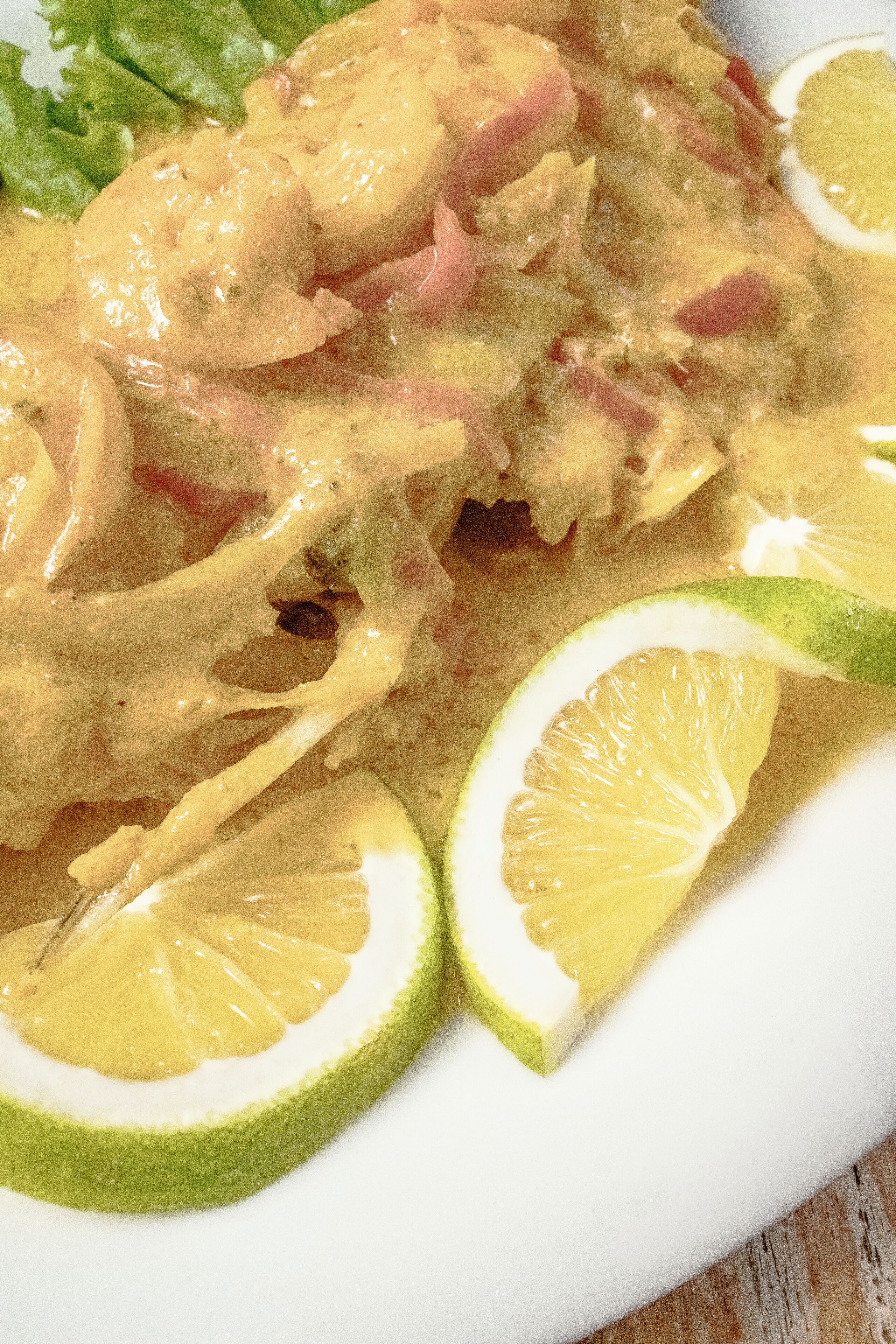 Un plato de comida con pollo en rodajas, gajos de lima y salsa cremosa.
