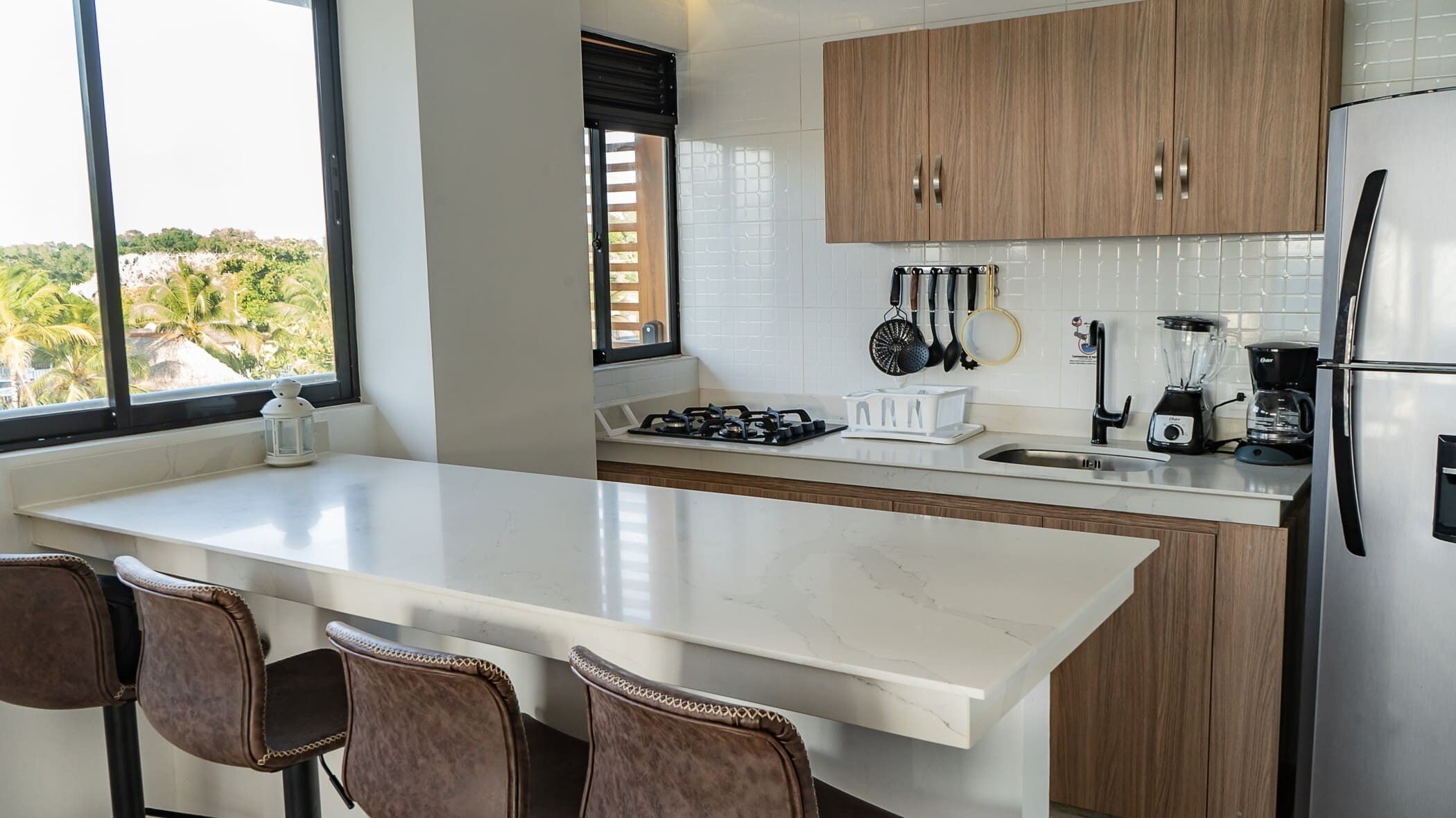 A modern kitchen with a large island, wooden cabinets, and stainless steel appliances.