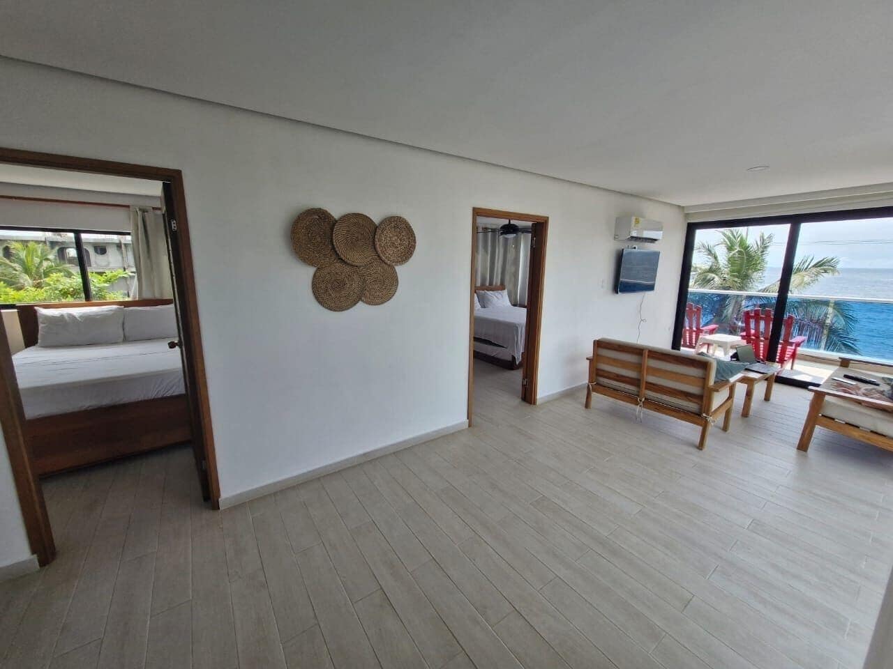 Ein geräumiges Zimmer mit einem Bett, einer Holzbank, einem kleinen Tisch und Blick auf den Ozean.