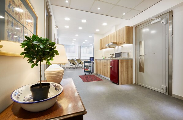 Enter a clean and contemporary space with a compact kitchen area featuring a wooden table, potted plant, and modern appliances.