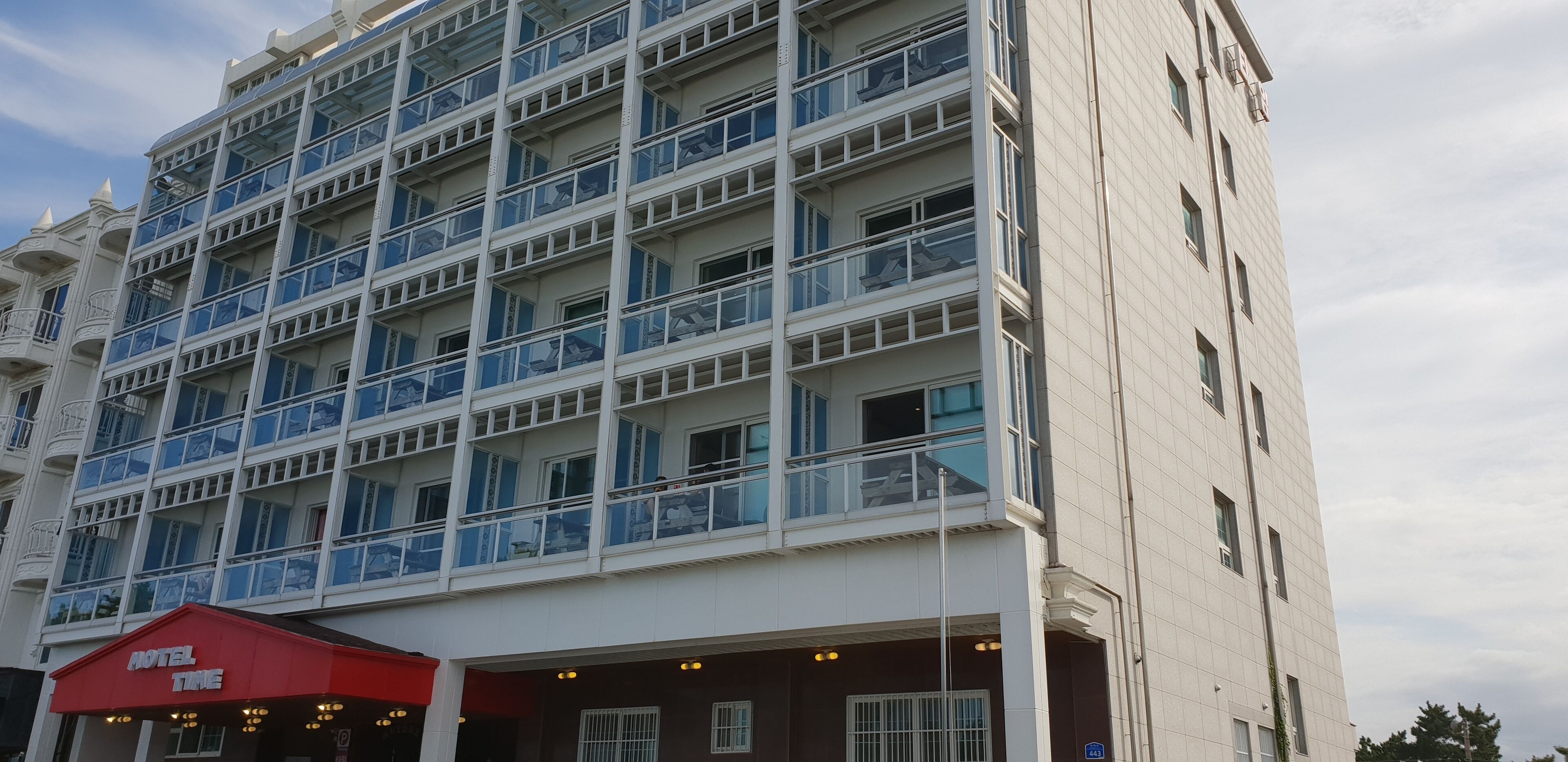 A multi-story hotel with a red awning labeled "HOTEL TIME" and a modern architectural design with balconies.
