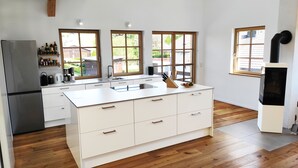 Una cocina moderna con una isla central, suelo de madera y grandes ventanas que ofrecen vistas al exterior.