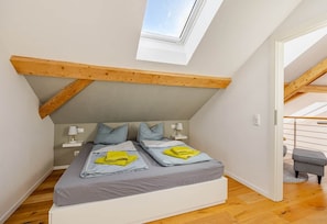 A bedroom with a sloped ceiling, a skylight, a bed with pillows, and a small bench. - Exclusive, sunny, stylish new-construction vacation apartment (Görisried)