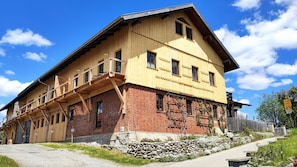 A traditional wooden building with a sloped roof, a stone foundation, and a wooden balcony.