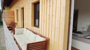 Una cabaña de madera con un porche cubierto, un sofá y un banco.