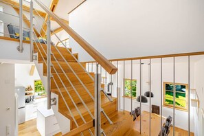 Ein modernes Interieur mit einer Holztreppe, einer Essecke und einer Küche.