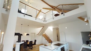 Un amplio espacio habitable con techo alto, una escalera, un comedor y una cocina.